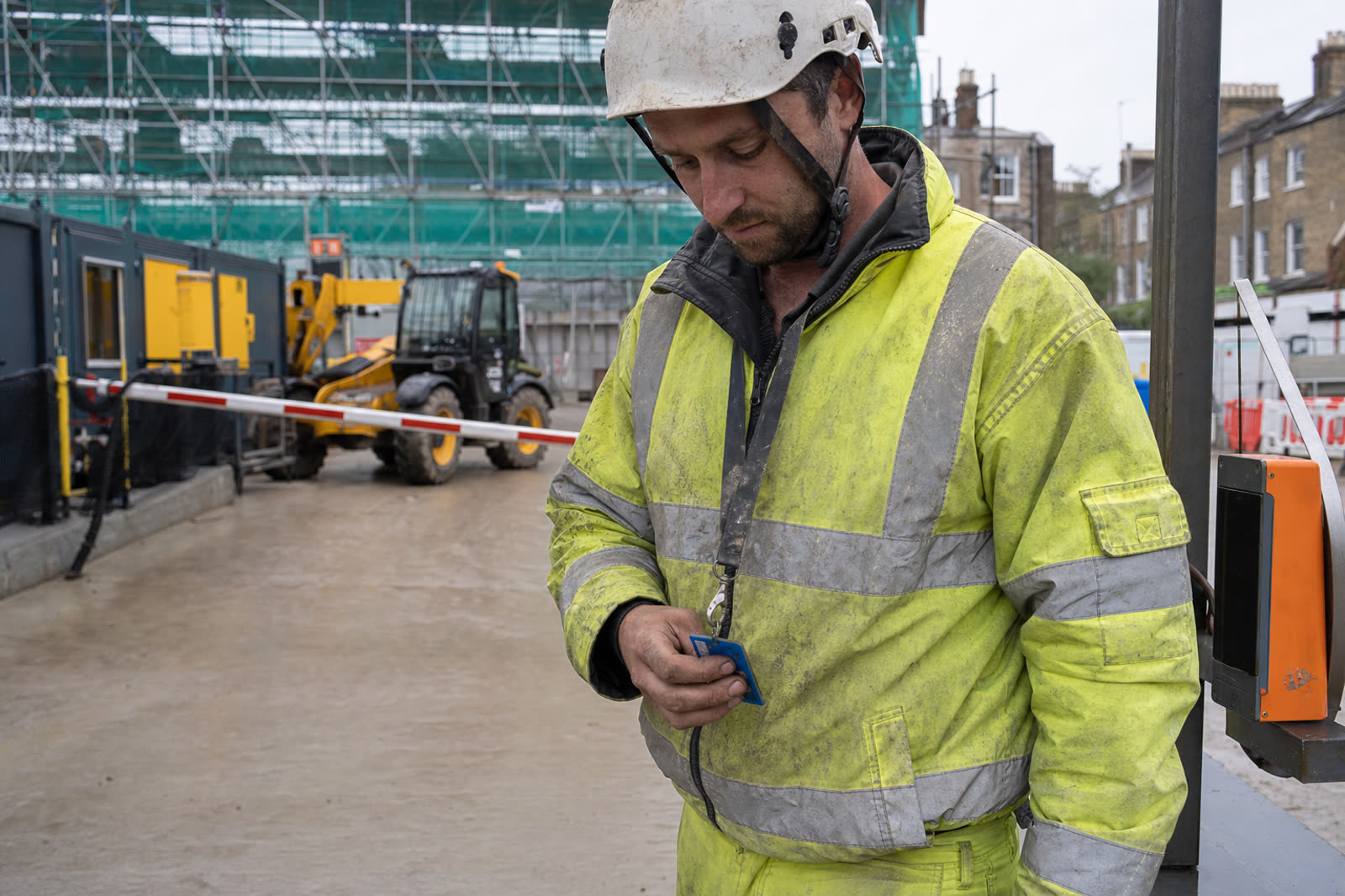 A tradesman checking his CSCS card before tapping in at a London site