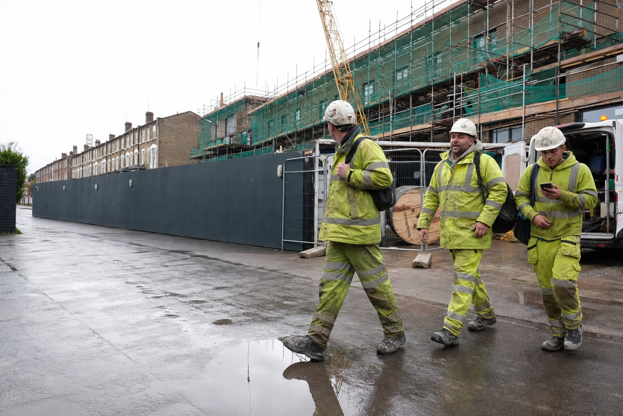 Workers leaving a London construction site on a wet overcast morning